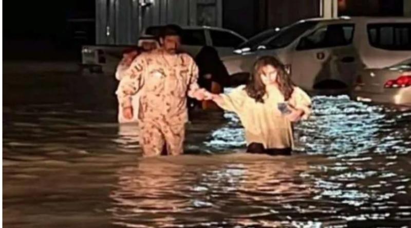 شرطي يساعد سيدة بسبب سيول الإمارات